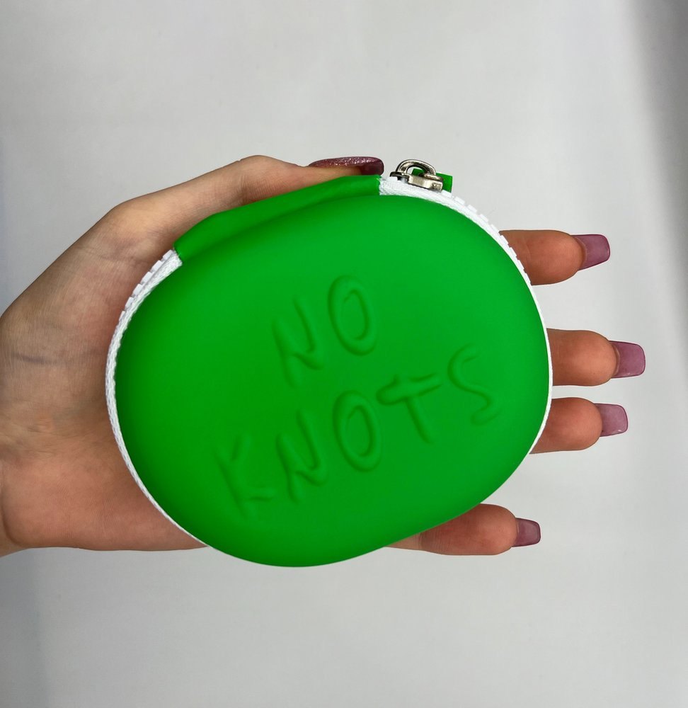 A hand holding the closed green No Knots case, which fills the palm.