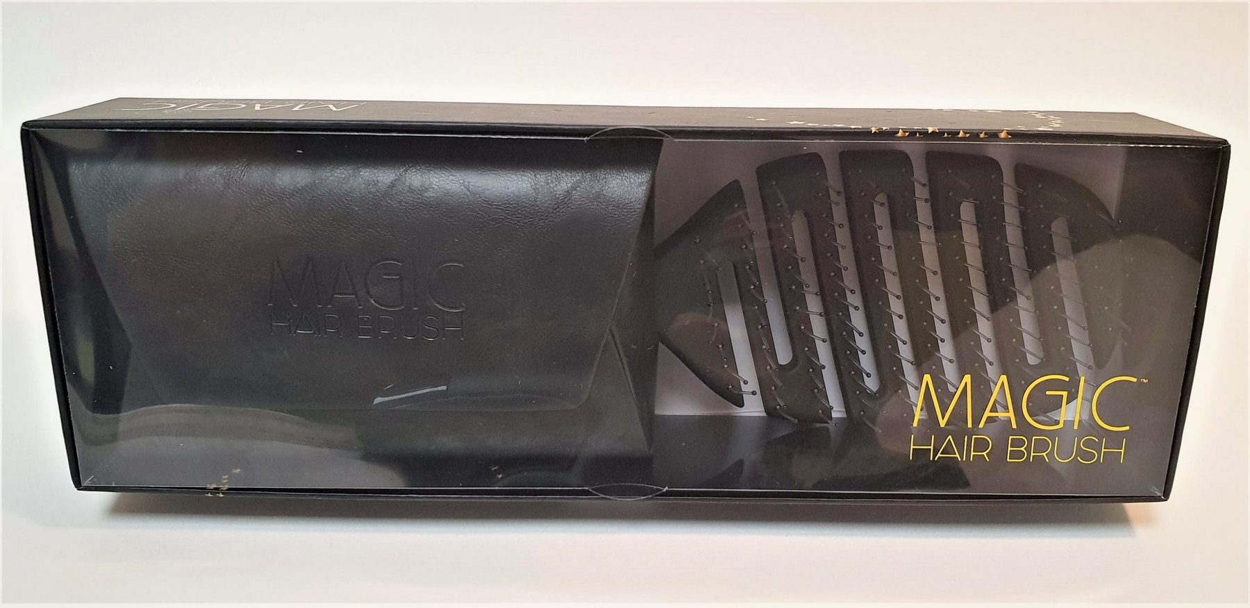 The black retail box printed with the gold Magic Hair Brush wordmark, holding the black wallet and brush behind clear film.