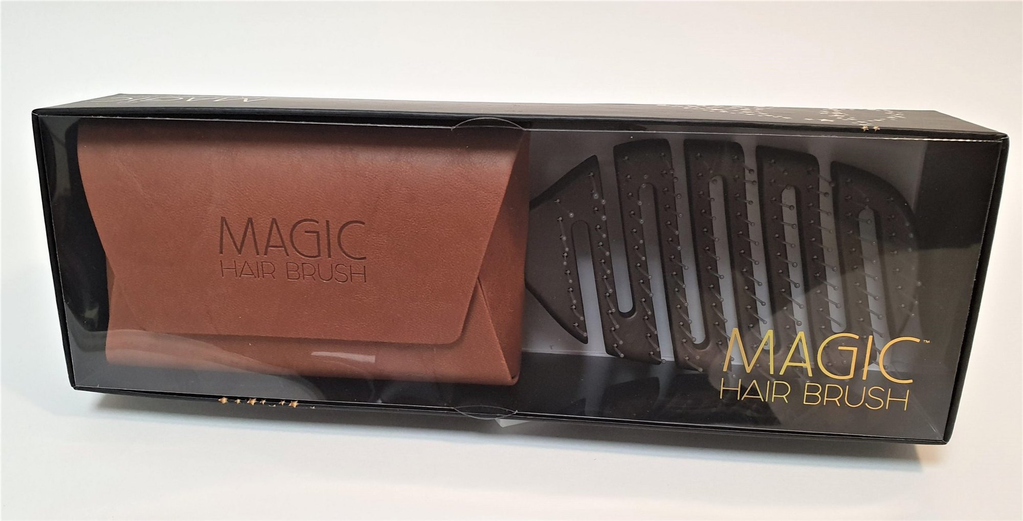 A black retail box printed with the gold Magic Hair Brush wordmark, holding a tan bronze wallet and a dark brush behind clear film.
