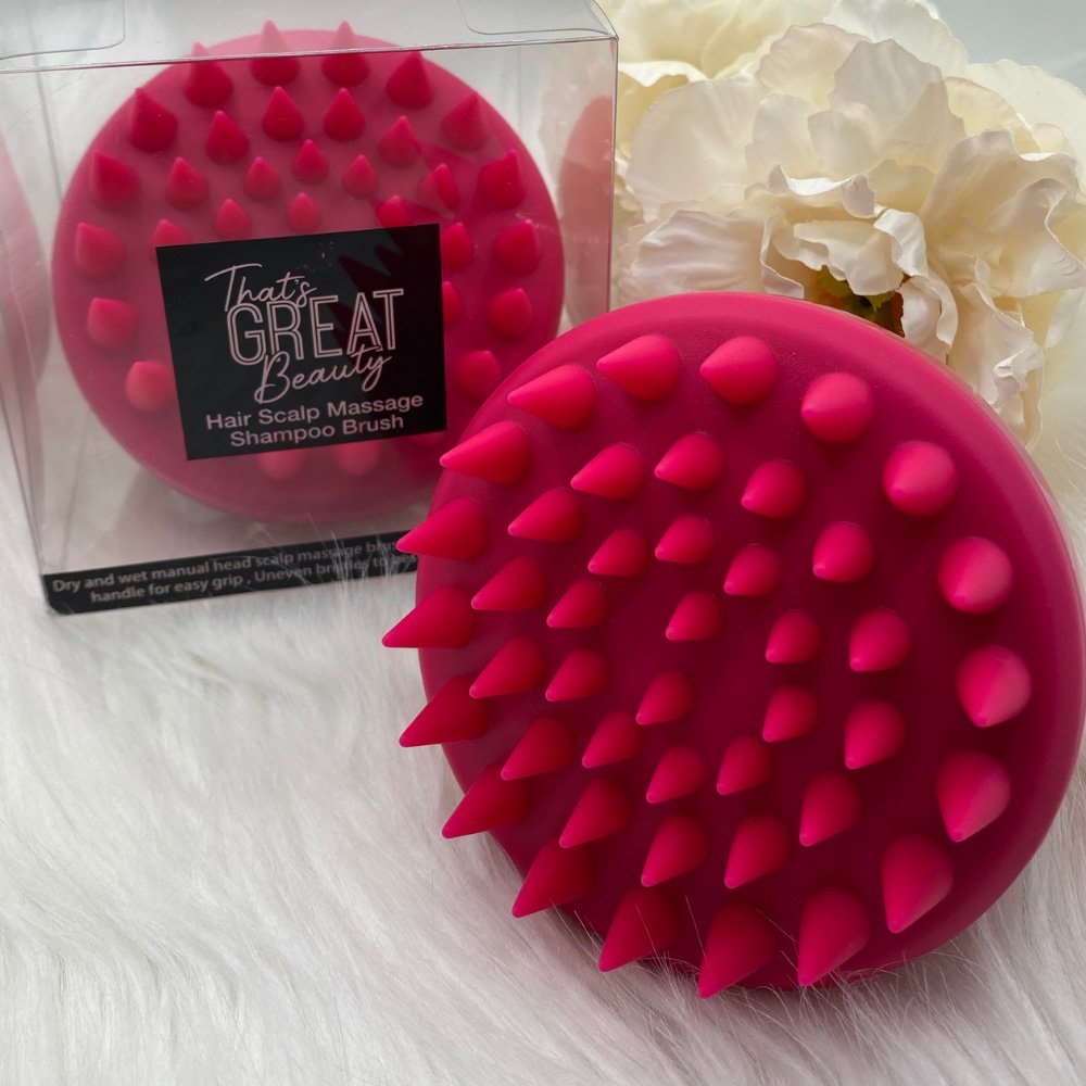 The pink silicone head massage shampoo brush photographed from above, showing its soft uneven bristles.